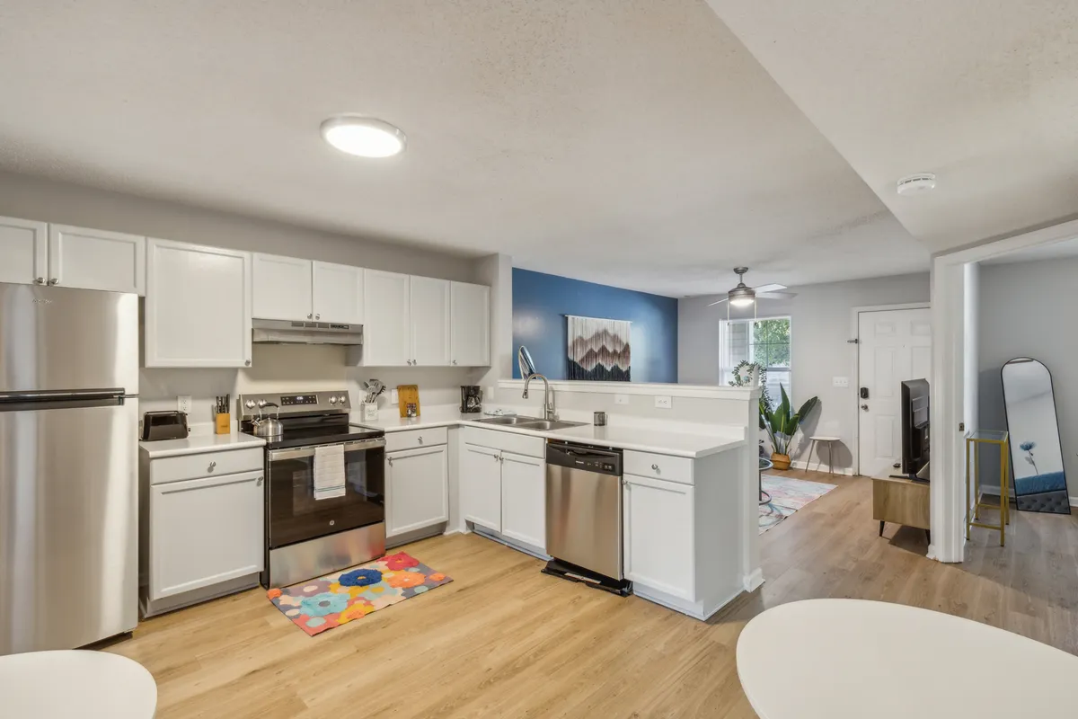 A welcoming, open-concept kitchen space featuring stainless steel appliances, a colorful rug that adds personality, and a layout that encourages both cooking and entertaining. The scene radiates warmth and is clearly designed for gatherings and culinary creativity.
