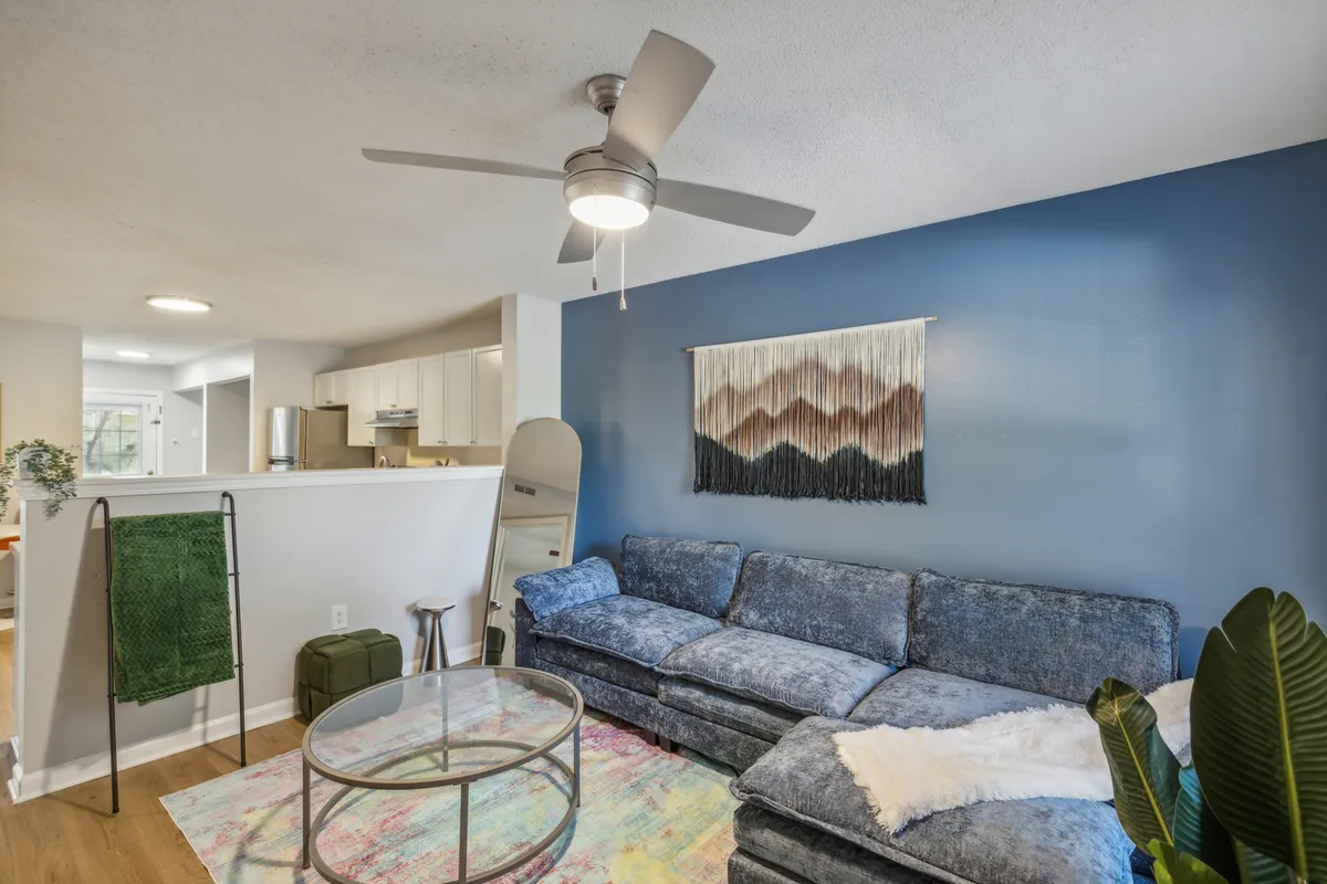 A cozy living room with a comfortable sofa, decorative wall hanging, and coffee table, arranged to invite relaxation and social moments. The scene exudes warmth and a sense of home, perfect for unwinding after enjoying Fayetteville’s local highlights.