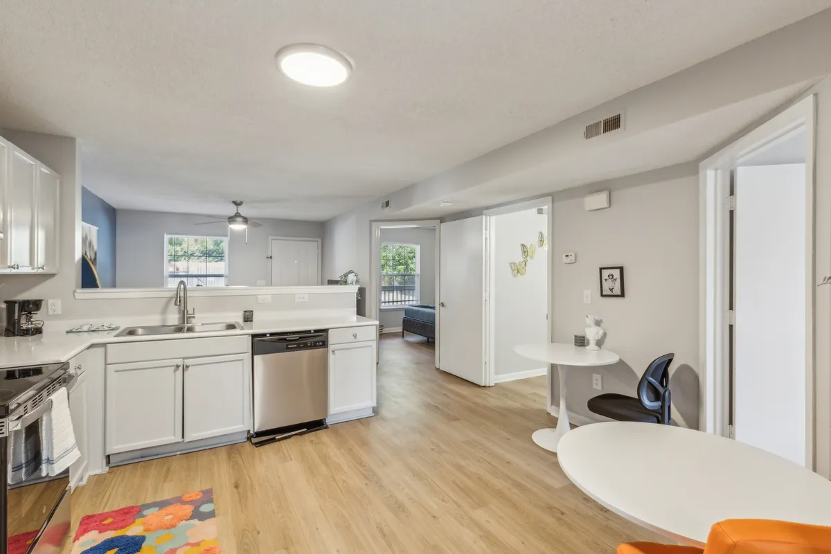 A bright, homey kitchen with sleek appliances, a round dining table set atop a colorful area rug, and ample natural light. The image invites viewers to imagine sharing meals and special moments in a cozy, practical setting.