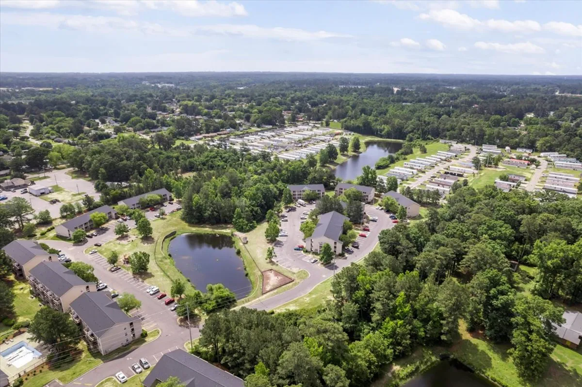 This serene exterior image features tranquil lakes bordered by lush green spaces and well-kept residential buildings. A gentle sunset bathes the scene in warm light, while families can be seen gathering for picnics and enjoying leisurely walks along the pathways.