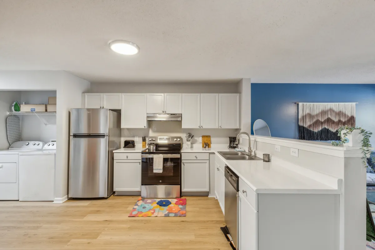 A kitchen scene with stainless steel appliances, a colorful rug, and an open layout ideal for cooking, casual dining, and socializing. The image exudes friendliness and functionality, emphasizing the space's flexibility for different occasions.